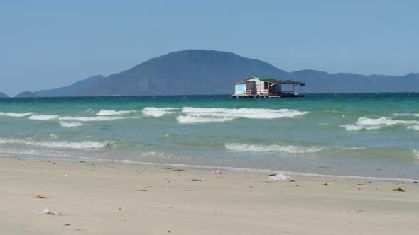 A Floating House in the Midst of Blue Ocean with Waves Breaking on the Seashore.