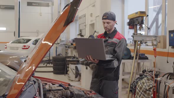 Mechanic Using Laptop for Car Diagnostic in Auto Service