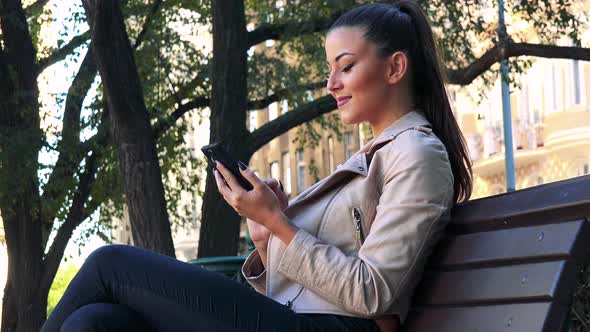 Young Beautiful Woman Works on the Smartphone and Smiles To Camera