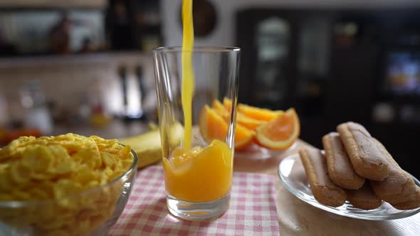 Pouring fresh orange juice into a glass on a rotating in kitchen, slow motion