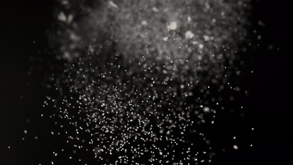 Dusting flour on black background. Slow Motion.