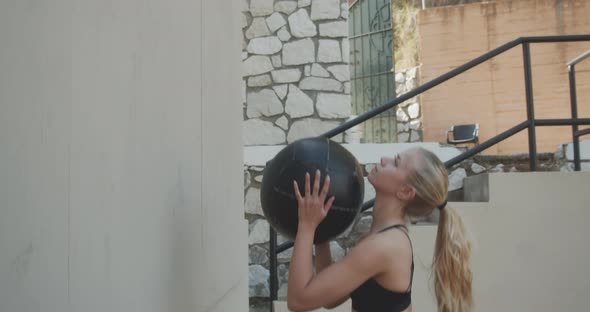 Young Woman Squatting To Throw And Catch Medicine Ball