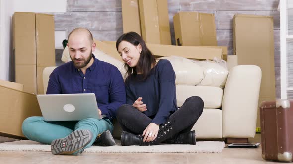 Couple Smilling While Sitting on the Floor of Their New Apartment