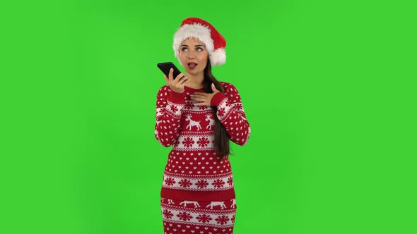 Sweety Girl in Santa Claus Hat Is Asking for Information on the Network Via Phone. Green Screen