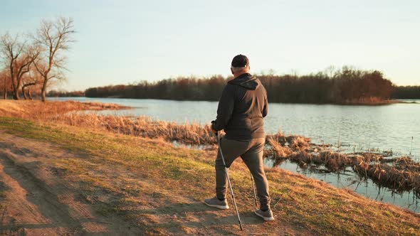 Nordic Walking  Active Man Working Out Outdoor Walks Along Shore of Lake