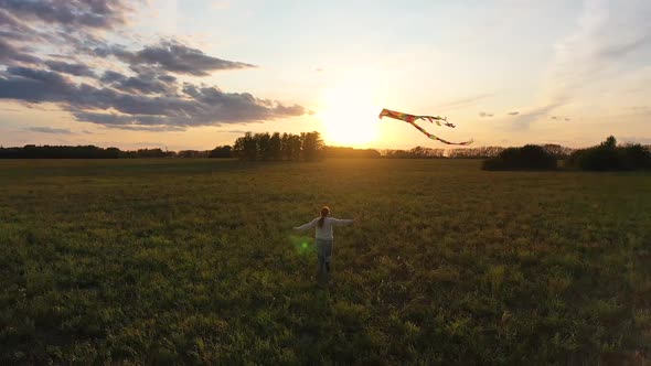 The Mother and Boy Run with a Kite on a Green Field