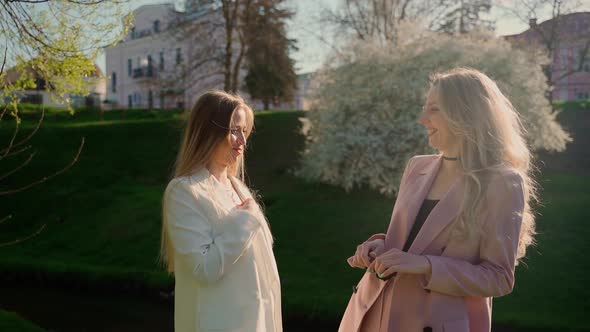 Young adult women spending time together outdoors. Two females persons talking in park outside