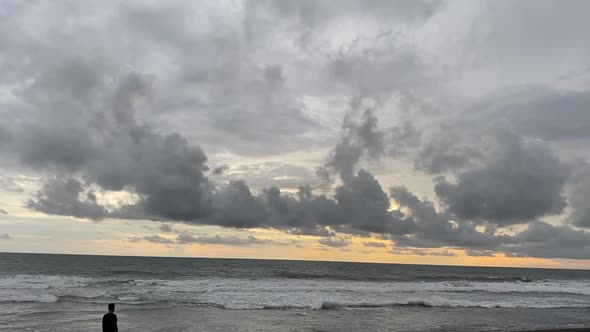 Silhouette Of A Man Standing On Beachfront With Splashing Waves During Sunset At Beach In Indonesia.