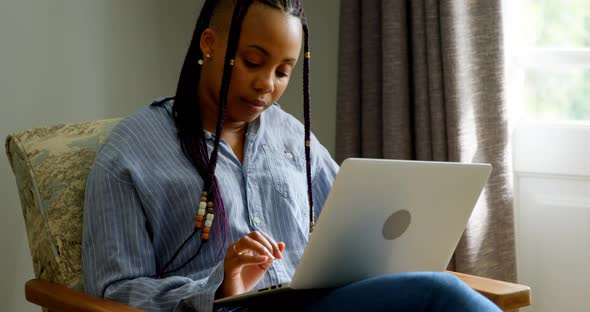 Front view of young black woman working on laptop in a comfortable home 4k