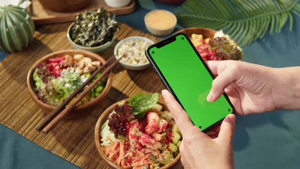 Hawaiian Poke Bowls Holding Smartphone with Chroma Green Screen Closeup