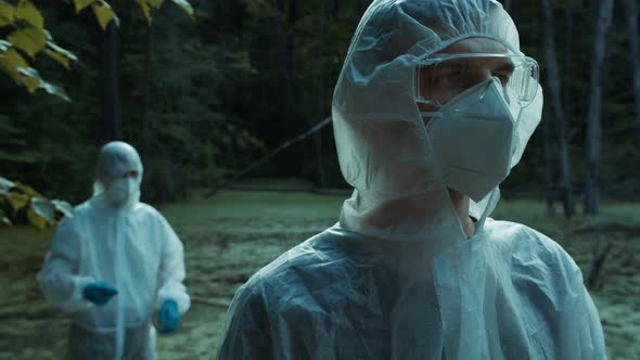 People Wearing Protective White Suits Taking Soil and Water Samples for Testing