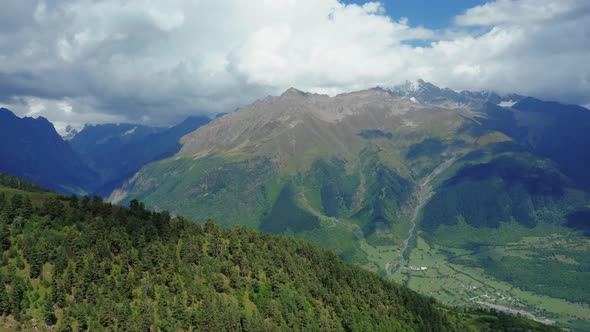 Aerial View From a Drone on the Forest Against Mountains and Cloudy Blue Sky