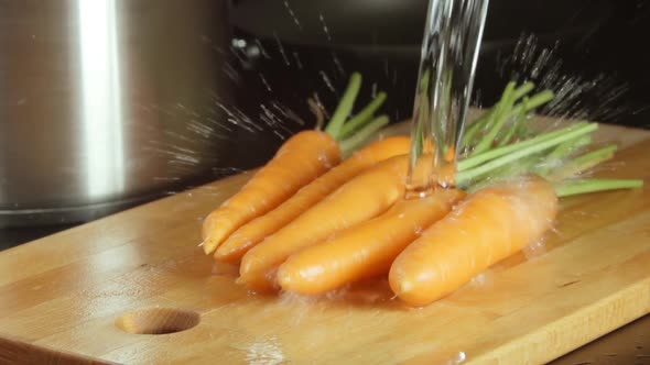 Water Stream Falls On A Carrots On A Cutting Board In A Kitchen