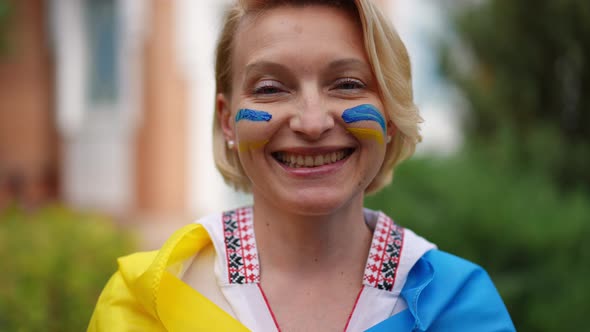 Headshot Portrait of Positive Woman in Embroidered Shirt and Ukrainian Flag Looking at Camera