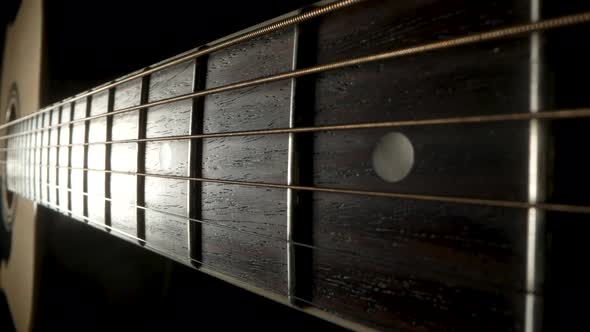 Camera Pans Over the Fretboard of a Classical Acoustic Guitar Against a Black Background