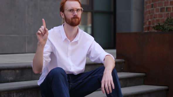Designer Sitting on Office Stairs Rejecting Offer By Waving Finger