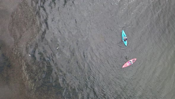 Aerial bird's eye view over tourists kayaking in the lake at daytime.