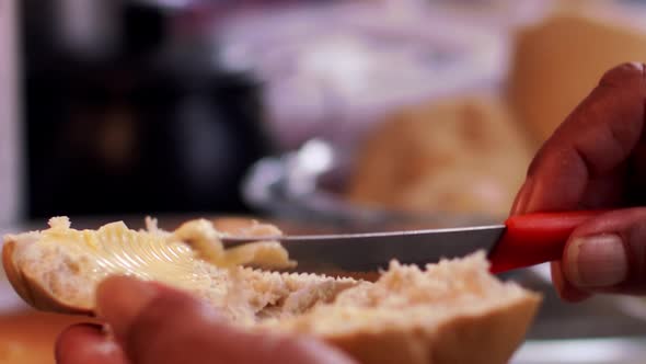 Spreading butter on fresh bred - isolated close up of hands with dark skin