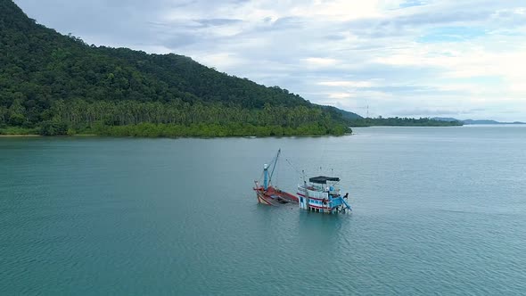 Drone circling around a half sunken boat in the sea.