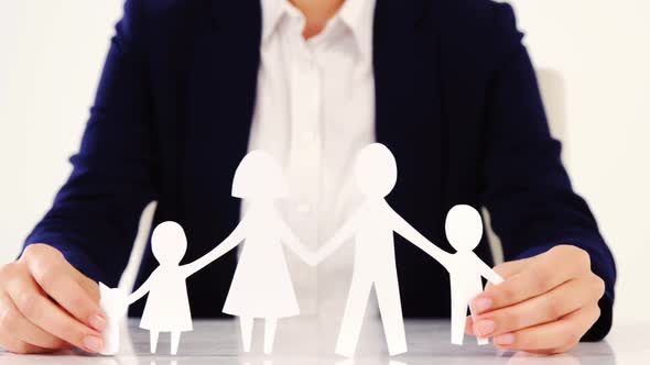 Businesswoman holding paper cut out of a family