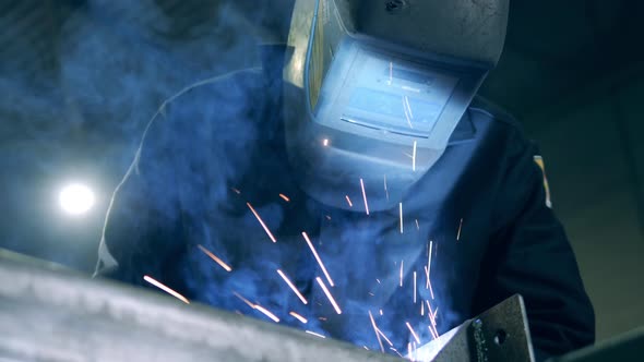 Professional Welder in a Helmet and Sparks Caused By Welding