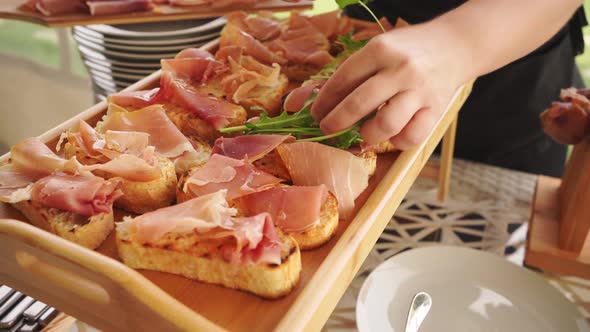 Hands Quickly Put Pieces of Dried Meat and Arugula on the Toast