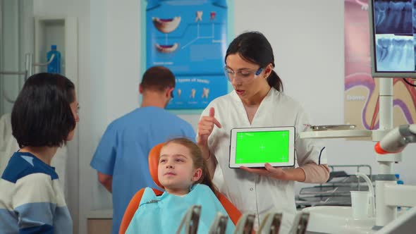 Dentist Showing Green Screen Display to Mother of Little Patient