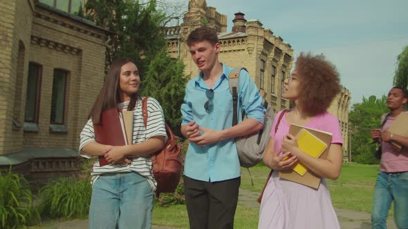 One Cheerful Student Catching Up Young College Friends Outdoors