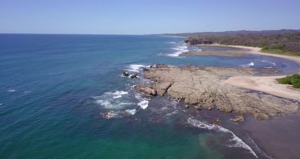 Aerial drone view of the beach, rocks and tide pools in Playa Palada, Guiones, Nosara, Costa Rica.