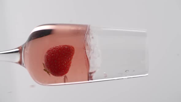 Vertical video, Close-up: strawberries fall into a glass of champagne