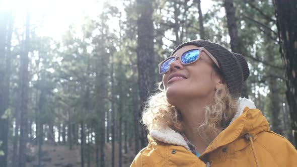portrait of beautiful woman looking and enjoying nature in a forest with some trees - traveling