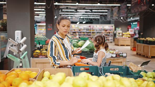 Lovely Family Mother and Little Daughter Buy Lemons in the Hypermarket in the Fruit Section