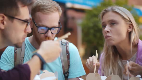 Close Up of Young Friends Enjoying Takeaway Meal Sitting in Outdoors Cafe