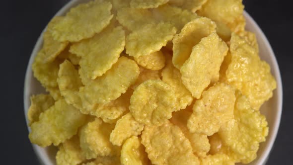 Crispy hot corn flakes with smoke rotating in bowl close up, dry healthy breakfast