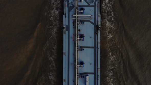 Heavy loaded blue tanker sailing foreward on a dark colored river using it navigating radar. Drone s