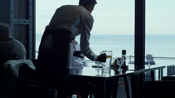 Wealthy Businessman Drinking Water Enjoying Scenic View in Modern Restaurant