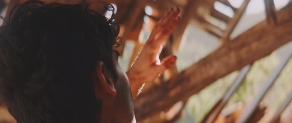 Man looking through broken roof with his hand up, close up