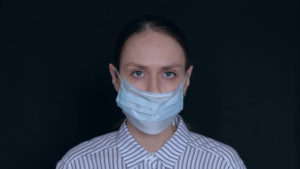 A Young Woman Puts Three Medical Masks on Her Face