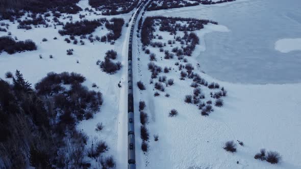 Train in a Valley followed in winter snow oil trailers tilt