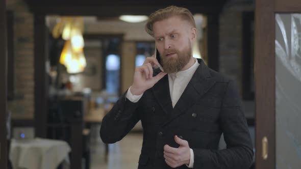 Portrait of a Successful Business Man with a Red Beard Talking on His Cell in an Expensive