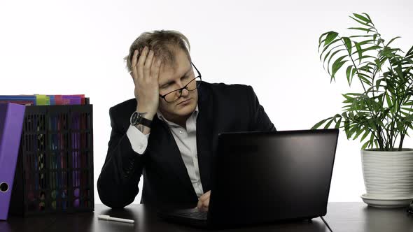 Tired Disheveled Businessman Working Hard in Office on Laptop at the Office Desk