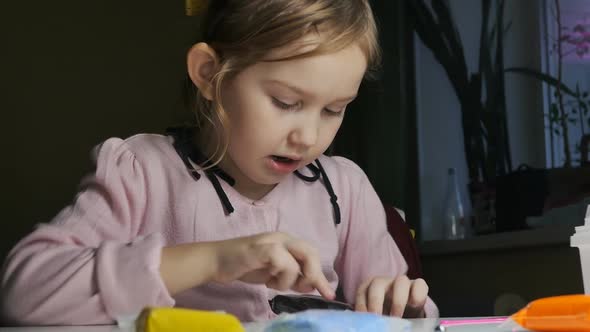 a Little Cute Girl in a Pink Sweater is Sculpting From Plasticine and Talking