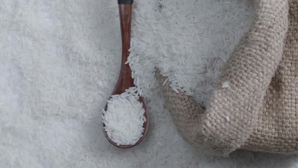 Raw Rice Grain In Rustic Bag And Wooden Spoon Rotate