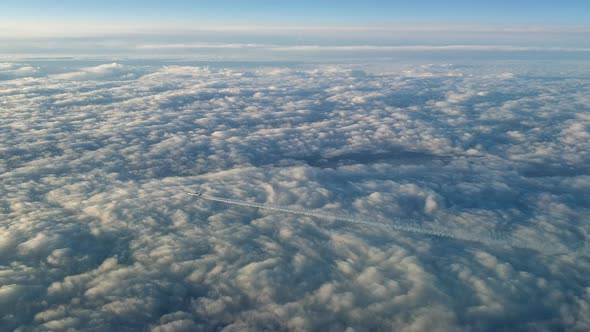 Incredible view from the cockpit of an airplane flying high above the clouds leaving a long white co