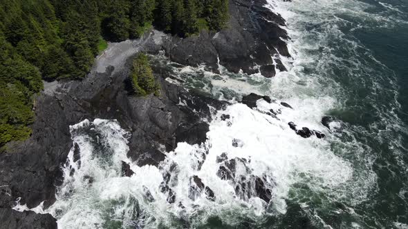 Zenith view of big waves crashing on rocky shore of botany bay from above. Drone slowlying to the si