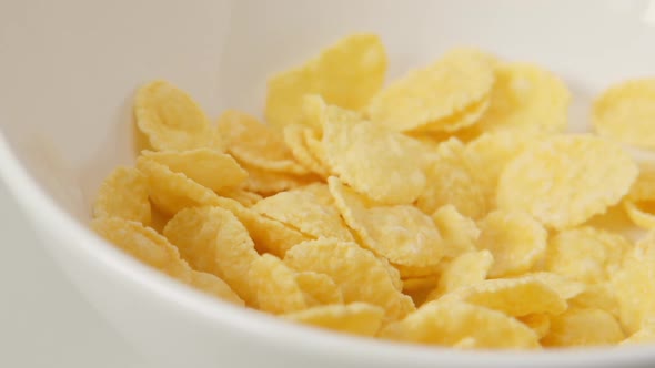 Corn flakes fall on white dish