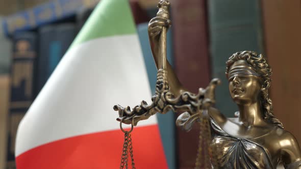 Statue of Lady Justice with Bookshelf with Books and Italy Flag Background