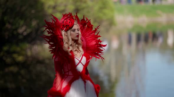 Red Queen in Fairy Forest Woman is Wearing Extravagant Dress is Walking Near Calm Picturesque Lake