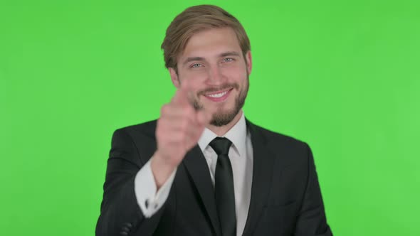 Young Businessman Pointing at the Camera on Green Background