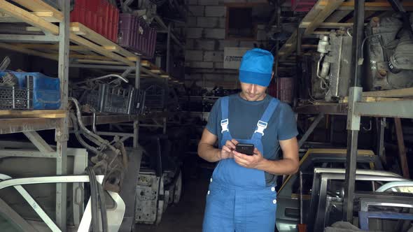 employee of auto disassembly, completes or checks car parts from tablet computer